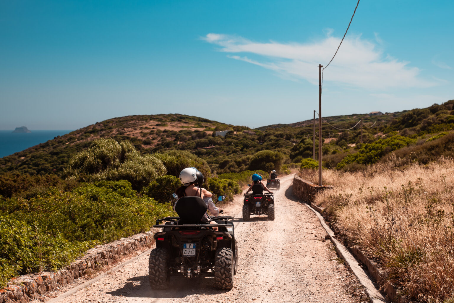 Pilota e passeggero col casco su un quad del Carolina Ranch, su una strada di Sant'Antioco